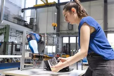Studentin zapft mit Hilfe eines Roboterarms Bier